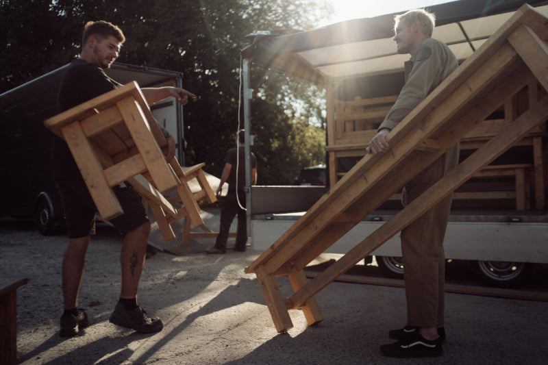 Mitarbeiter von Kawentsmann laden Tische in einem Transporter zur Veranschaulichung des Profils eines Bewerbers zum Monteur