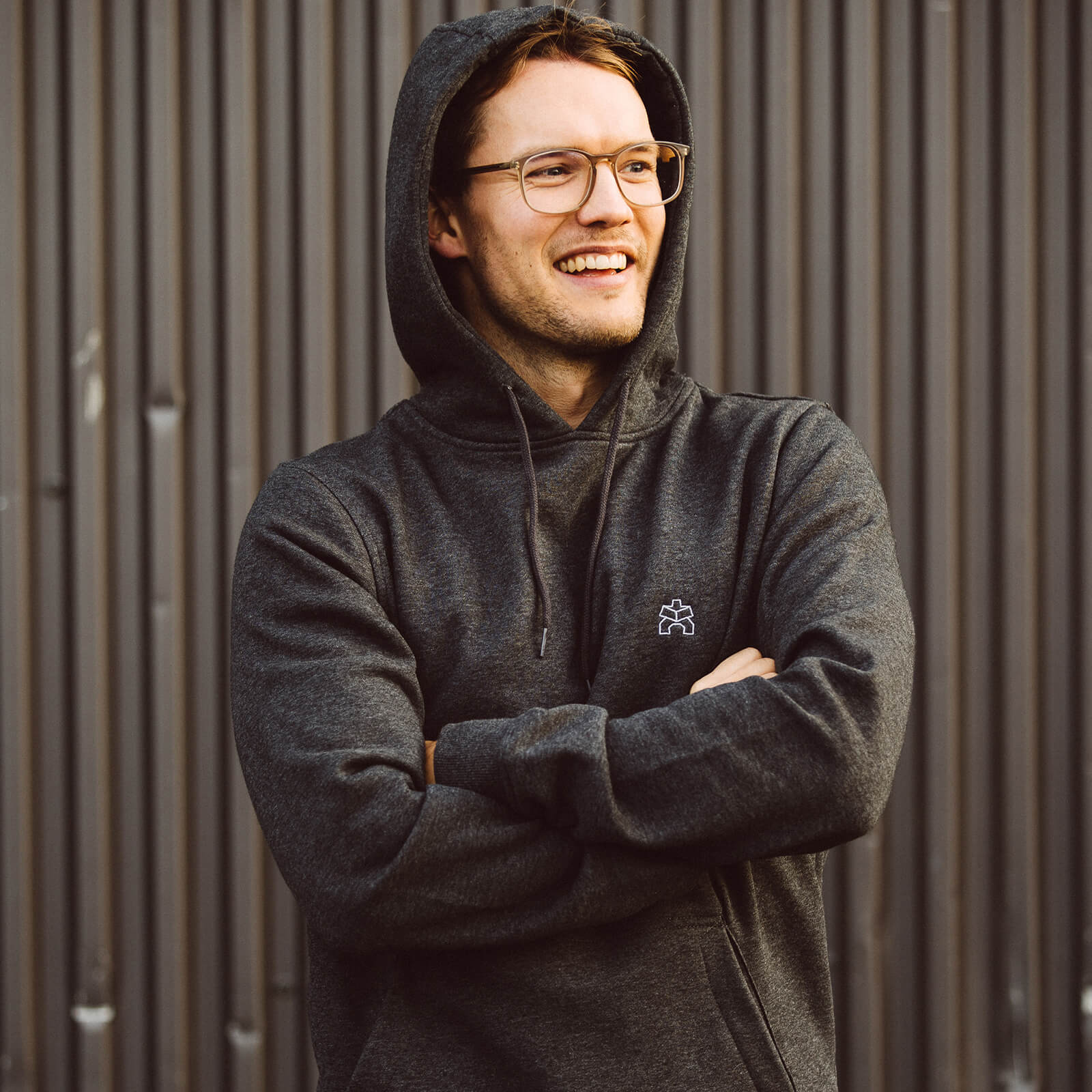 Hoodie in Dunkelgrau meliert mit einem weißen Logo-Stick unisex getragen von einem Mann