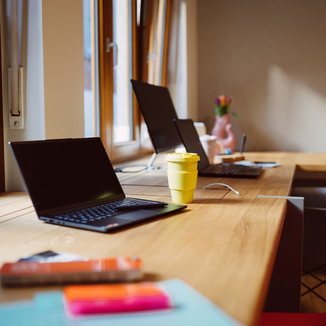 Schreibtisch mit Laptops und Kaffeebecher zur Veranschaulichung der Ausbildung zu E-Commerce Kaufmann/-frau bei KAWENTSMANN