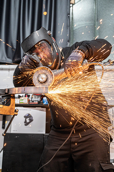 Handwerker schleift Tischgestell aus Metall