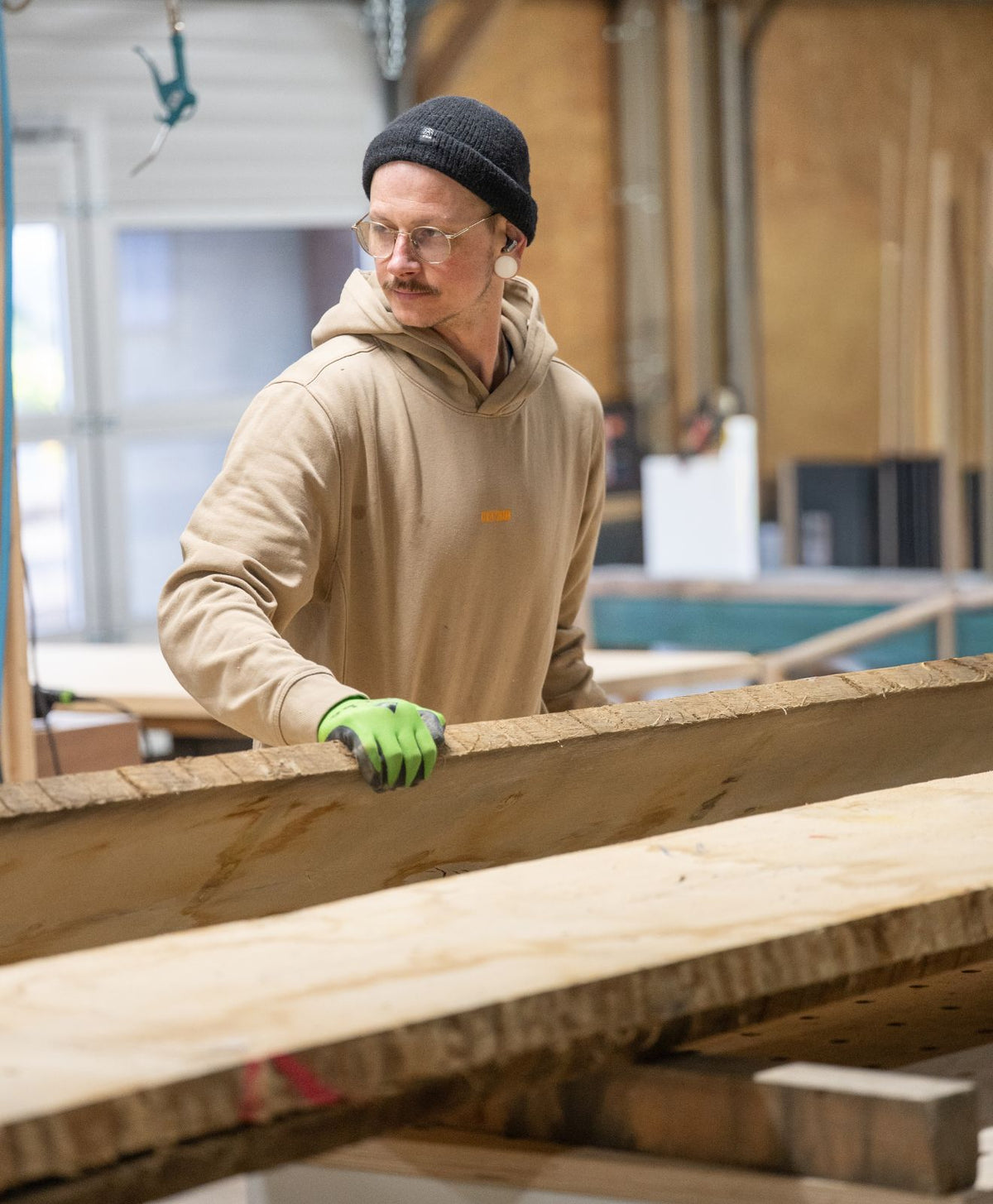 Tischler Billi in der Werkstatt mit Holzbohlen zur Darstellung der Handarbeit mit Holz